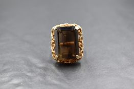 A 9ct gold smoky quartz set dress ring, the emerald cut quartz measuring approximately 28mm x