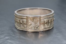 A Victorian silver hinged bangle having bar and dot applique decoration bordering an engraved
