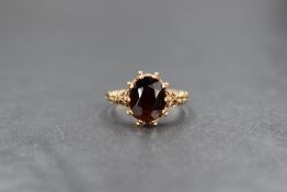 A 9ct gold red paste set ring, the central oval cut red paste having ornate moulded shoulders,