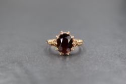 A 9ct gold red paste set ring, the central oval cut red paste having ornate moulded shoulders,