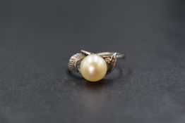 A 14ct white gold pearl set ring, the central cultured pearl having a cream lustre in an engraved