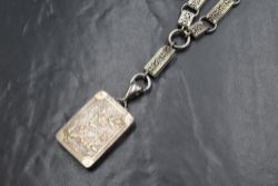 A Victorian white metal locket of rectangular form having rose & yellow gold coloured floral