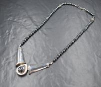 A silver and hematite statement necklace, the tapered articulated silver links with a central pear