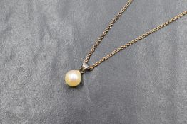A cultured pearl pendant with a white metal loop mount on an 18' rose gold chain bearing plaque