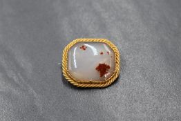 A yellow metal dendritic agate set brooch, the octagonal translucent agate having red dendritic