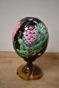 A contemporary ostrich eggshell upon a wooden base, featuring transfer floral and foliate