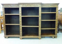 A 1920s oak breakfront open bookcase with an arrangement of seven height adjustable shelves, on a