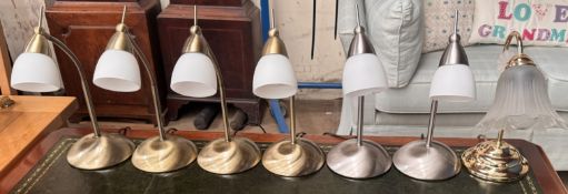 A set of four brass table lamps with opaque glass shades together with a pair of satin steel table