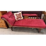 A Victorian chaise longue upholstered in red with a spindle back on turned legs and casters