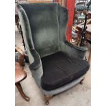 An upholstered wing back arm chair with outswept arms on cabriole legs and pad feet
