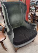 An upholstered wing back arm chair with outswept arms on cabriole legs and pad feet