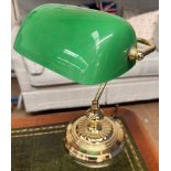A desk lamp with a green glass shade and brass column