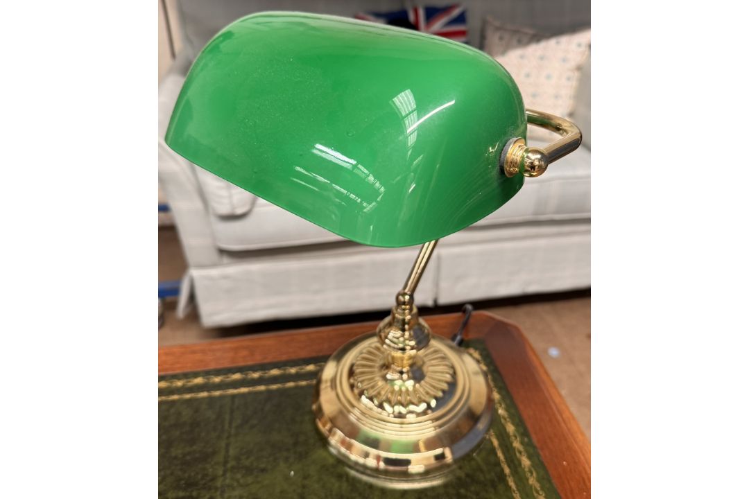A desk lamp with a green glass shade and brass column