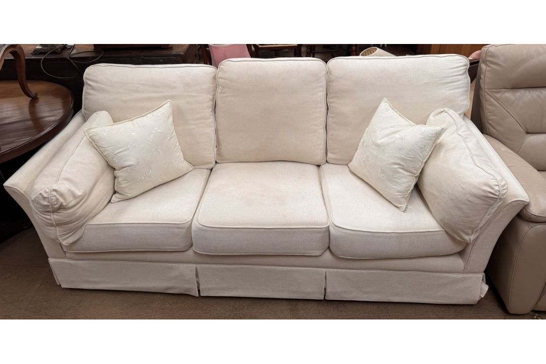 A cream upholstered three seater settee