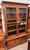 A large pine bookcase with a moulded cornice above a pair of glazed doors,