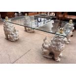 A glass topped coffee table with a rectangular top on four seated dog of foo legs, 122cm x 68.