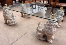 A glass topped coffee table with a rectangular top on four seated dog of foo legs, 122cm x 68.