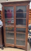 A 20th century mahogany bookcase with a moulded cornice above a pair of glazed cupboard doors on