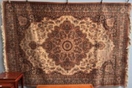 A large rug with a cream and brown ground with a central medallion and spandrels the guard stripes