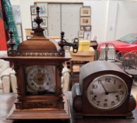 A walnut mantle clock with a domed top and finials above a silvered dial and Arabic numerals
