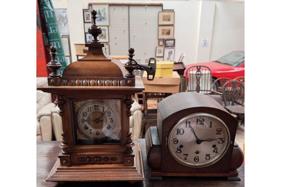 A walnut mantle clock with a domed top and finials above a silvered dial and Arabic numerals