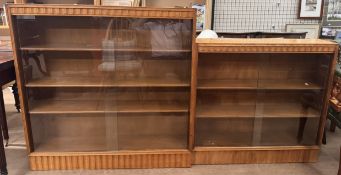 An oak bookcase with a rectangular top above a shaped frieze with matching base and sliding glass