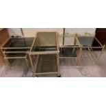 A brass framed and smoked glass tea trolley together with a similar nest of three tables and two