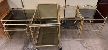 A brass framed and smoked glass tea trolley together with a similar nest of three tables and two