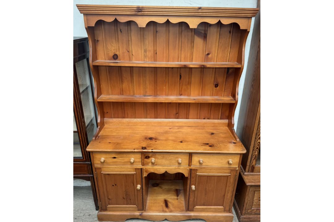 A pine dresser with a moulded cornice above two shelves, the base with three drawers,