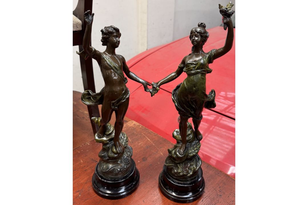 A pair of spelter figures depicting a young girl and a young boy on naturalistic bases,