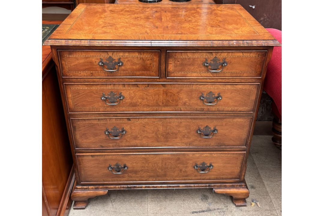 A reproduction walnut chest with a rectangular crossbanded and herringbone strung top above two