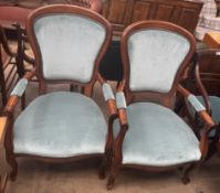 A pair of reproduction elbow chairs with pad upholstered back and seat on shaped legs