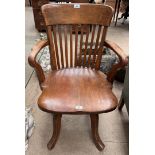 An elbow chair with a slat back and solid seat on four splayed legs