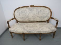 An early 20th century French Louis XV style gilt wood carved settee, upholstered in traditional
