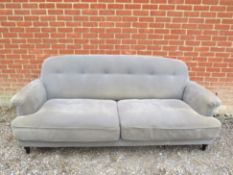 A large grey coloured two seater sofa, on turned ebonised supports. H88cm x W220cm x D90cm approx.