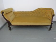 An early 20th century beech framed chaise longue, button upholstered in a mustard fabric. H70cm x