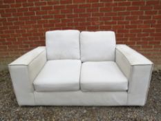 A cream coloured two seater sofa. H63cm x W152cm x D92cm approx. Condition report: good order.