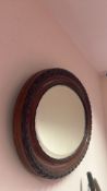 An oval wall mirror with a moulded timber frame, the outer border carved with repeating oval