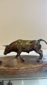 Bronze-toned metal model of a bull in low-headed stance, mounted on a polished banded stone plinth