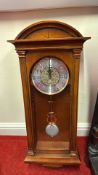 Wall-hung pendulum clock in arched wooden case