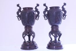 A pair of bronze vases, each of baluster form with dragon-scroll handles, relief panels of birds and