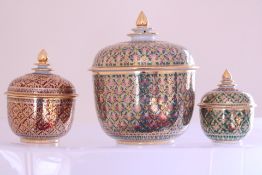 A group of gilt-decorated lidded porcelain jars, each painted with repeating floral motifs on