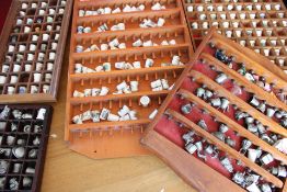 Collection of souvenir porcelain and pewter thimbles in wooden display cases
