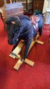 Black plush rocking horse with leather saddle and wooden base