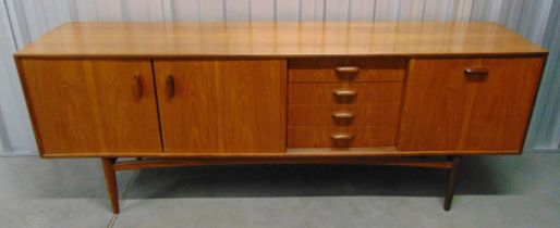 A mid 20th century rectangular teak sideboard with cupboards and drawers on four turned supports,