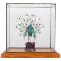 A fine unmarked silver filigree and enamel ornamental peacock, on carved wood stand, in glass