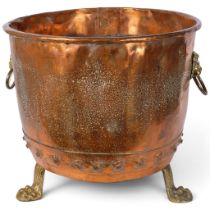 A large riveted copper log bin, with brass lion ring handles and brass lion paw feet, diameter 49cm,
