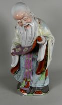 A Chinese Famille Rose Porcelain Figure of Shouxing, the God of Longevity, holding a scroll with