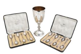 A George V silver goblet, and two cased sets of silver spoons