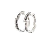 A pair of white and black diamond hoop earrings